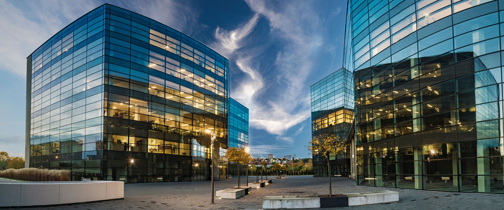 A group of glass office buildings shimmer in the fading light of dusk.